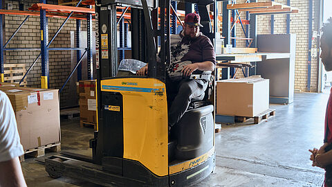 Persoon bestuurd een heftruck in een magazijn.