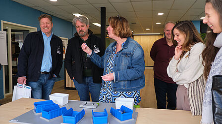 Groep mensen bekijkt met plezier een praktijkopdracht.