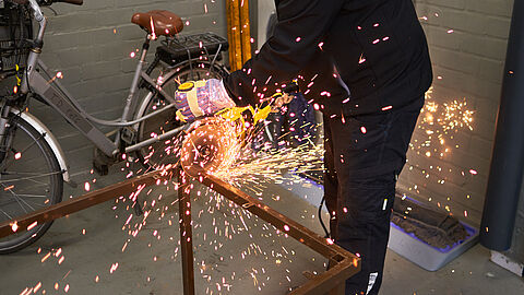 Man last een metalen frame met spattende vonken.