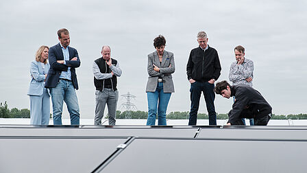 Groep mensen kijkt met interesse naar de installatie van zonnepanelen.