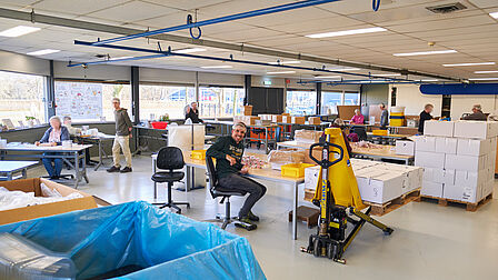 Grote witte productieruimte met verschillende mensen aan het werk.