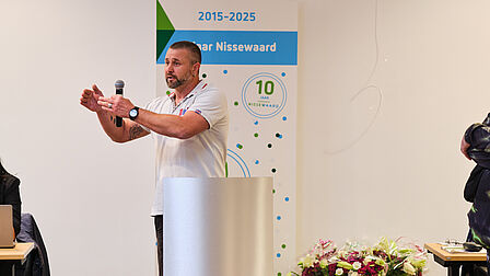 Man maakt handgebaren tijdens presentatie.