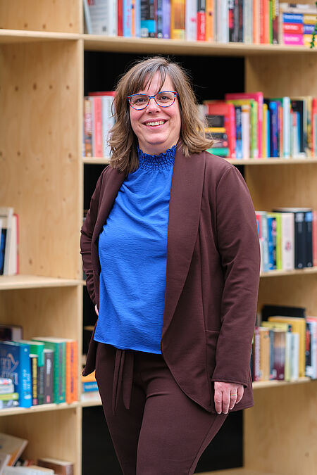 vrouw met bril poseert voor een boekenkast