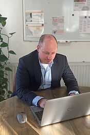 Portret van Roeland achter een laptop.
