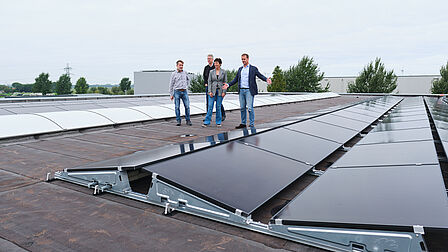 Groep mensen op het dak naast zonnepanelen.