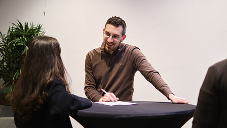 Werkgever met kandidaat aan een statafel.