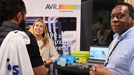 Mensen aan een statafel, roll-up banner met bedrijfslogo.