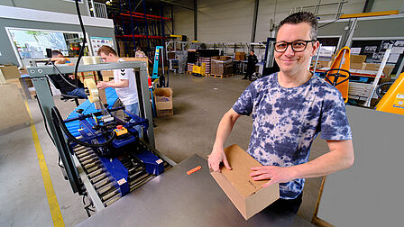 Iemand is een doos aan het inpakken voor een productielijn.