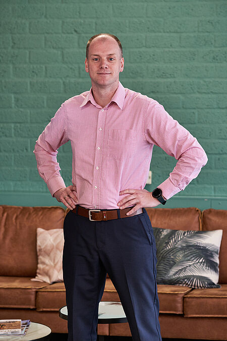 foto van een poserende man in rose overhemd.