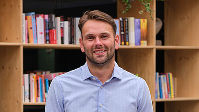 portret van een man in blauw overhemd en spijkerbroek