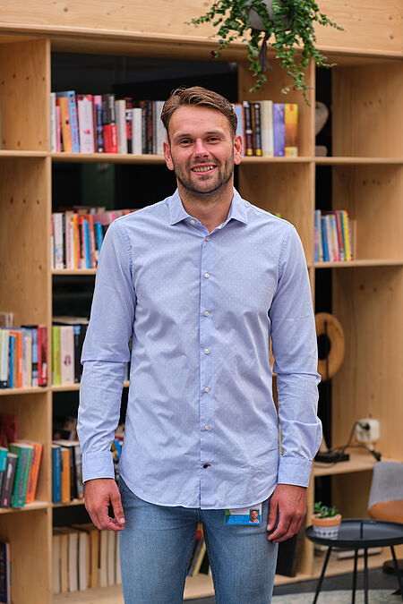 portret van een man in blauw overhemd en spijkerbroek