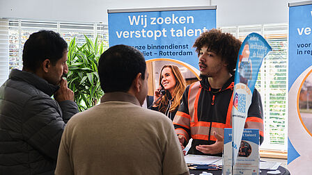Mensen in gesprek aan een statafel met vlaggen, promotiemateriaal.